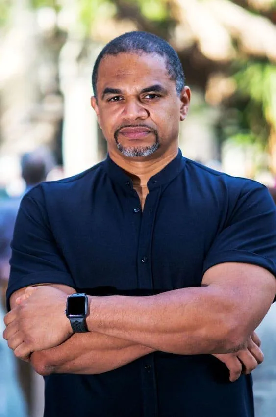 Retrato de Seemore Johnson, coach y formador de Nomadic Closer Academy, con los brazos cruzados, transmitiendo seguridad y liderazgo, especializado en mentalidad, control emocional y toma de decisiones en entornos de alta presión.